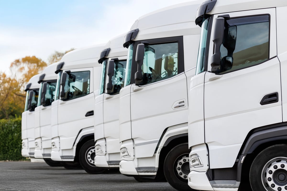 Fleet of new modern white trucks parked in line row outdoors
